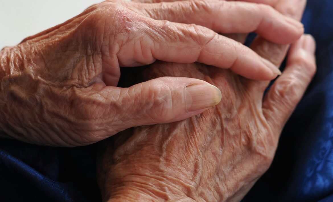 Folded hands of an elderly person resting in their lap